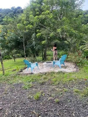 a woman is standing between two blue benches at Cabaña La paz in Alajuela City