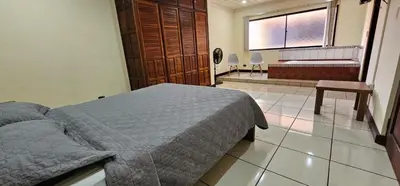 a bedroom with a bed and a bench and a window at Apartotel Obelisco San José Aeropuerto in San José