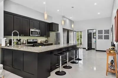 a kitchen with black cabinets and a counter with bar stools at Casa Dasani - Beautiful House with private pool in Santa Rosa