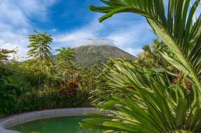 a mountain in the distance with a swimming pool and plants at Hotel Hot Springs Sueno Dorado in Fortuna