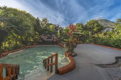 a pool with a water slide in a backyard at Hotel Hot Springs Sueno Dorado in Fortuna