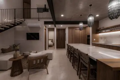 a kitchen and living room with a long bar with chairs at The Town at Praia in Jacó