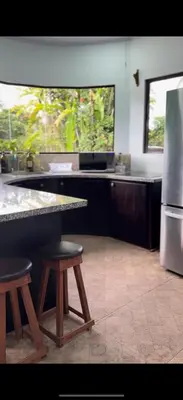 a kitchen with a counter and two stools and a refrigerator at Tres Diamantes Casa Completa in Parrita