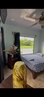 a bedroom with a bed and a table and a window at Tres Diamantes Casa Completa in Parrita