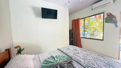 a bedroom with a bed and a tv on the wall at Tres Diamantes Habitaciones con piscina in Parrita