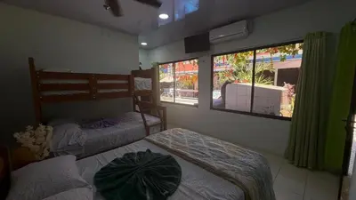 a bedroom with two beds and a window at Tres Diamantes Habitaciones con piscina in Parrita