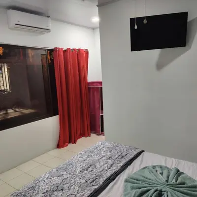 a room with a bed and a window with red curtains at Tres Diamantes Habitaciones con piscina in Parrita