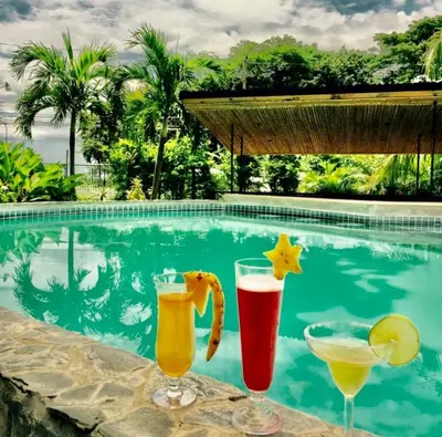 three drinks on a table next to a swimming pool at Flamingo 107 Cabins apartment, 100mts from the beach in Playa Flamingo