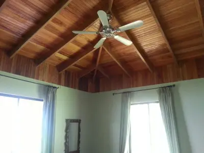 a ceiling fan in a room with two windows at Toucan Villa in Caña Blanca