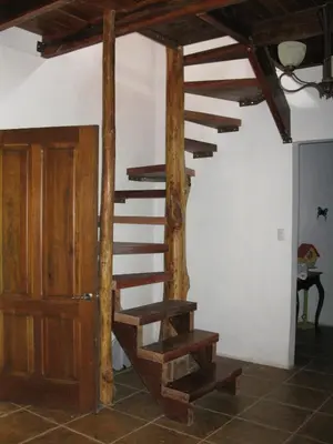 a wooden spiral staircase in a room with a door at Toucan Villa in Caña Blanca