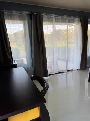 a living room with two large windows with curtains at Hacienda Santa Elena in Santa Cruz