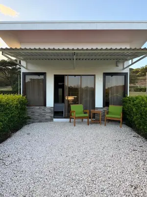 a house with two green chairs and a table at Hacienda Santa Elena in Santa Cruz