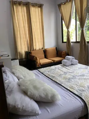 a bedroom with a bed with white pillows and a couch at Casa Aguacte in Quepos
