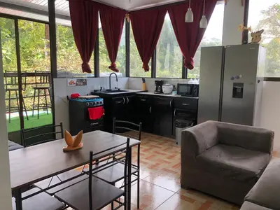 a kitchen with a table and a chair and a refrigerator at Casa Aguacte in Quepos