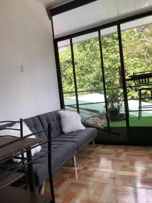 a living room with a couch and large windows at Casa Aguacte in Quepos