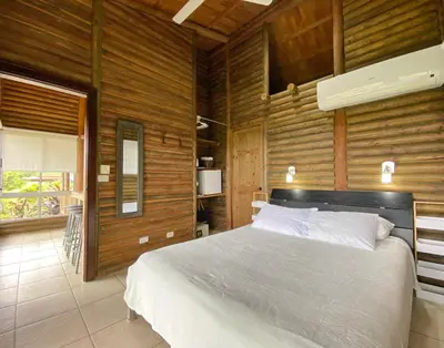 a bedroom with a large bed in a room with wooden walls at Horizon Hotel & Yoga Center in Santa Teresa Beach