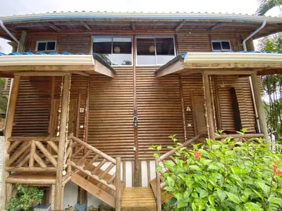a large wooden house with a porch and a deck at Horizon Hotel & Yoga Center in Santa Teresa Beach