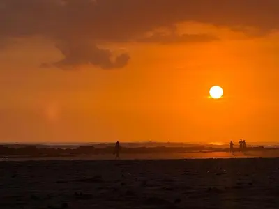 a group of people walking on the beach at sunset at Brianne's Place in Playa hermosa