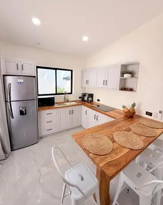 a kitchen with a wooden table and a refrigerator at Brianne's Place in Playa hermosa