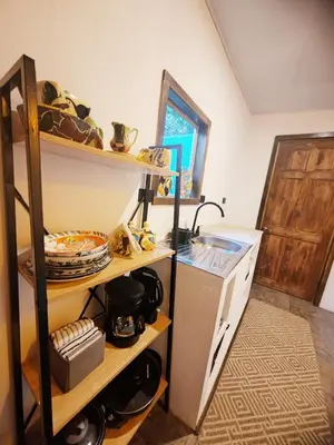 a kitchen with a sink and a shelf with dishes at Cozy Café Studio in El Copey