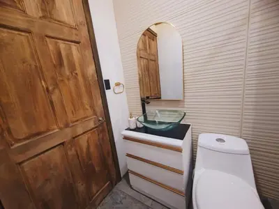 a bathroom with a toilet and a sink and a wooden door at Cozy Café Studio in El Copey