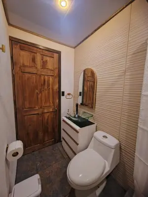 a bathroom with a toilet and a wooden door at Cozy Café Studio in El Copey