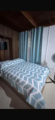 a bed with a blue comforter in a bedroom at Quinta Don Ebal in Guácimo