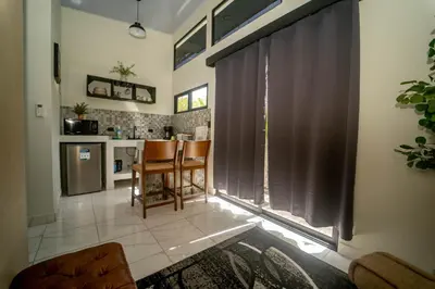 a living room with a window with curtains and a kitchen at Inta Tiny House in Fortuna