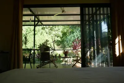 a bedroom with a bed and a view of a patio at Casa de la Diversidad - La Casita - Ojochal in Ojochal