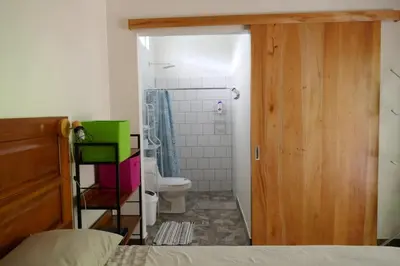 a bedroom with a bathroom with a toilet and a shower at Casa de la Diversidad - La Casita - Ojochal in Ojochal