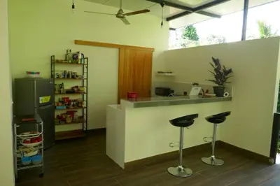 a kitchen with a counter with two bar stools at Casa de la Diversidad - La Casita - Ojochal in Ojochal