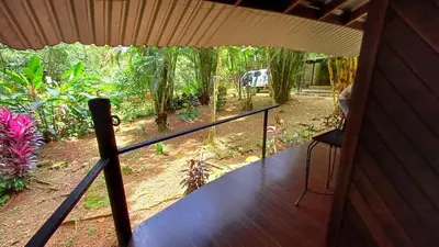 a porch of a house with a view of a garden at Wooden Cabin with deck Over Creek, walk to beach in Dominicalito