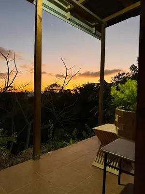 a patio with a bench and a sunset in the background at Magic Lodge - Cirrí, Naranjo