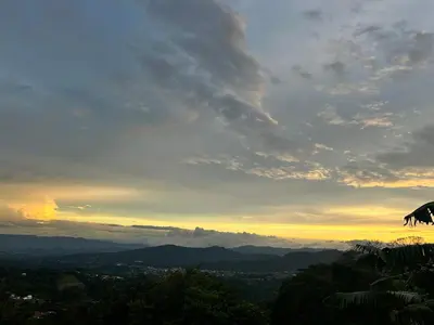 a view of a sunset from a hill with trees at Magic Lodge - Cirrí, Naranjo