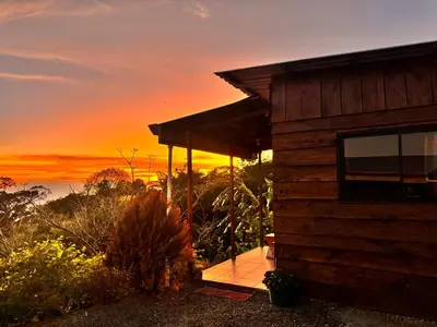 a wooden cabin with a sunset in the background at Magic Lodge - Cirrí, Naranjo