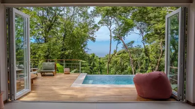 a room with a view of a pool and trees at Casa Terra - Modern House with Ocean Views in Santa Teresa Beach