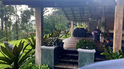 a person sitting on the porch of a house with plants at Finca Lilly in Upala