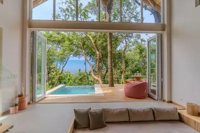 an open living room with a large window and a pool at Casa Solana - Modern House with Ocean Views in Santa Teresa Beach
