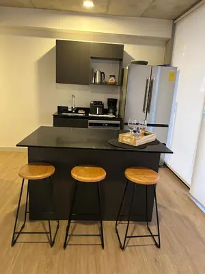 a kitchen with a black counter with stools and a refrigerator at Chill Lodge Babylon Tower 506 in San José