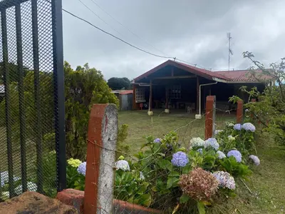 a fence in front of a house with flowers at Poasito Room in Fraijanes