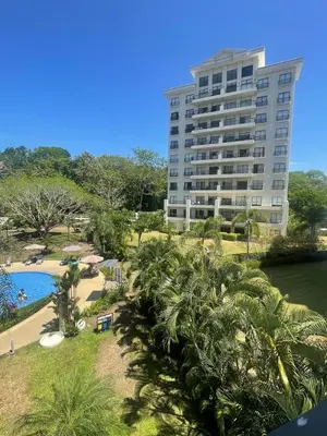 a large building with palm trees in front of a pool at Jacobay condominio 3303 in Jacó