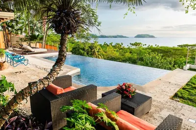 a villa with a pool and a palm tree at Casa de Los Suenos in Potrero