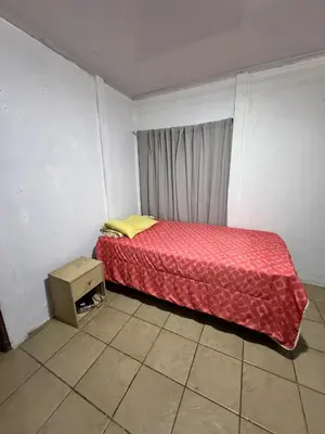 a small bedroom with a bed with a red blanket at Hospedaje Loma Verde in Chiles