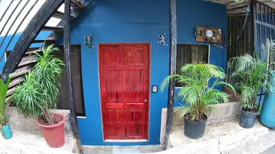 a blue house with a red door and potted plants at Small blue house in Quepos