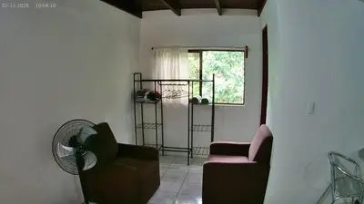 a living room with two chairs and a window at Small blue house in Quepos
