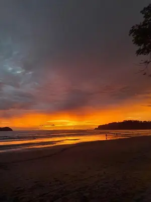 a sunset on a beach with the ocean at Small blue house in Quepos