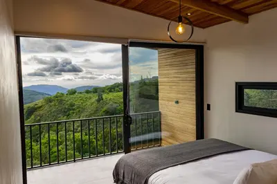 a bedroom with a bed and a balcony with a view at BìBO Horizon House in Monteverde Costa Rica
