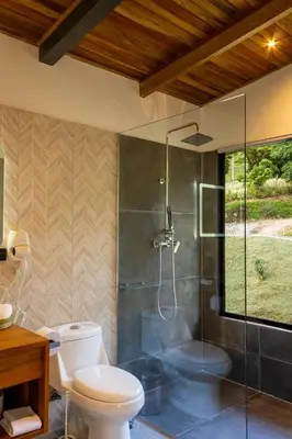 a bathroom with a toilet and a glass shower at BìBO Horizon House in Monteverde Costa Rica