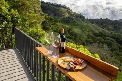 a table with wine glasses and wine bottles on a balcony at BìBO Horizon House in Monteverde Costa Rica