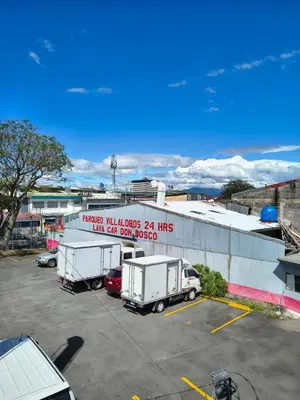 a parking lot with two white trucks parked next to a building at Vilma Friendly Guesthouse - RC in San José